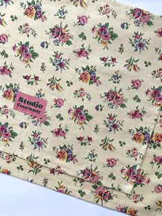 the fabric has flowers on it and is white with pink, yellow and green colors