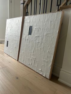 two pieces of cardboard sitting on top of a hard wood floor next to a banister