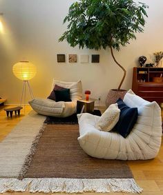 a living room filled with furniture and a tree in the corner on top of it