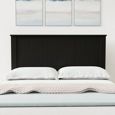 a black headboard with two paintings above it