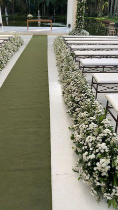 the aisle is lined with white flowers and greenery on either side of the aisle