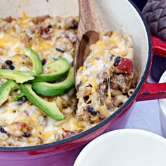 a casserole dish with meat, beans and avocado is shown in a red pan