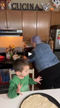 an older woman is helping a young boy bake food in the kitchen with his hands