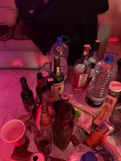 the table is full of alcohol bottles and empty cups, including one that has been placed on it