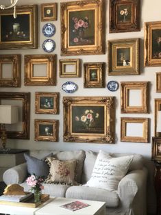 a living room filled with furniture and lots of framed pictures on the wall above it