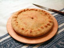 a pie sitting on top of a wooden plate next to a knife