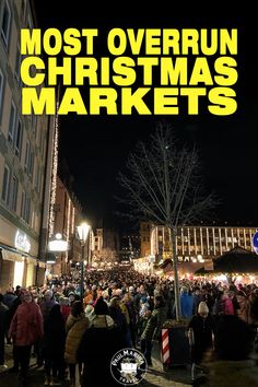 a crowd of people walking down a street next to tall buildings with christmas lights on them