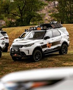 two white suvs are parked in the grass