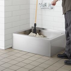 a man standing in front of a sink with a mop and cleaning cloths