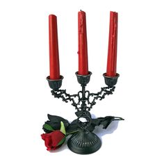 three red candles sitting on top of a metal candelabra filled with roses