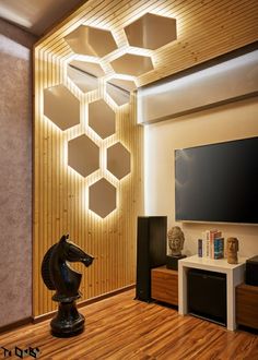 a living room with wooden flooring and modern lighting fixtures on the wall, along with a horse statue