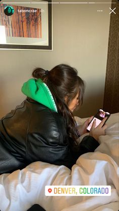 a woman laying on top of a bed holding a cell phone in her hand and looking at the screen