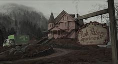 a pink house sits on top of a hill with a sign in front of it