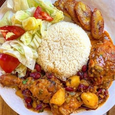 a white plate topped with rice and meat next to salad on top of a wooden table