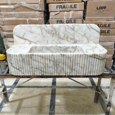 a white marble bench sitting on top of a metal stand in front of stacks of boxes