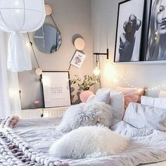 a white bed topped with lots of pillows next to two pictures on the wall above it