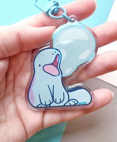 a hand holding a plastic keychain with a cartoon dog on it's side