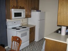 a white stove top oven sitting inside of a kitchen next to a wooden table and chairs