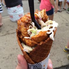 a person holding up an ice cream cone with toppings on it and a fork sticking out of it