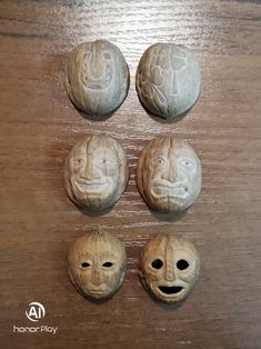 four carved clay faces sitting on top of a wooden table