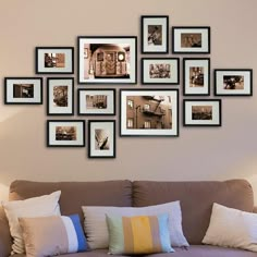 a living room filled with lots of framed pictures on the wall above a brown couch