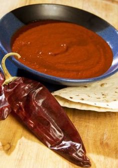 a hot sauce in a bowl next to some tortillas