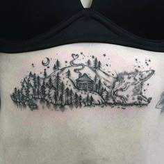 a woman's stomach with a wolf and cabin tattoo on the side of her belly