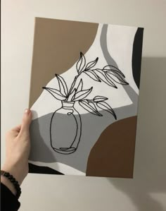 a person holding up a piece of art that looks like a vase with flowers in it