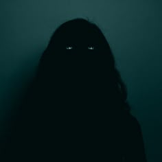 a person with long hair and eyes in the dark