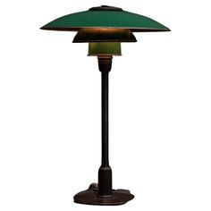 a lamp that is on top of a stand with a green shade over it's head