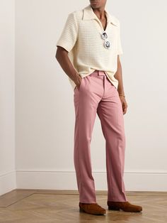 a man standing in front of a white wall with his hands on his hips wearing pink pants