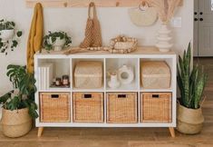 a white shelf filled with baskets and plants