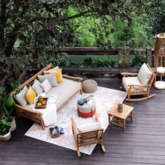 an outdoor patio with wooden furniture and plants on the deck, surrounded by greenery