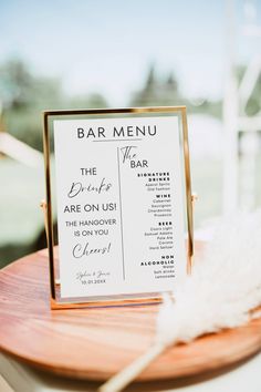 a menu sitting on top of a wooden table next to a white feather in front of a window