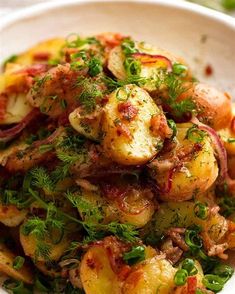 a white bowl filled with potatoes covered in herbs