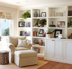 a living room filled with lots of white furniture and bookshelves covered in plants