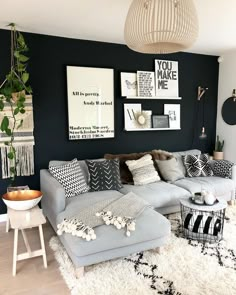 a living room with black walls and white rugs on the floor, large gray sectional couch