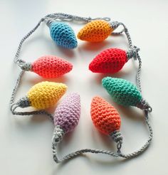 crocheted christmas lights are displayed on a white surface with gray string and hooks