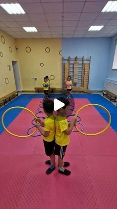 two children are playing with hoop rings in the gym