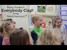 a group of children standing around each other in front of a book shelf with the words everybody clap written on it