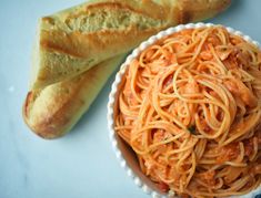 a bowl of spaghetti and bread on a table