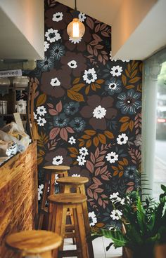 a wall with flowers painted on it and stools in front of the bar area