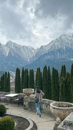 a woman walking down a walkway next to mountains