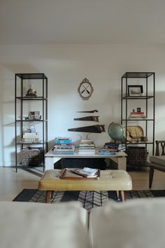 a living room filled with furniture and a clock on the wall above it's shelves