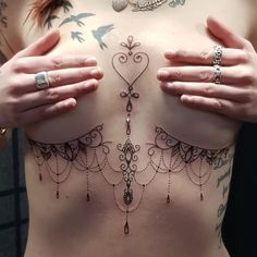 a woman with tattoos on her chest and hands holding onto the top of her stomach