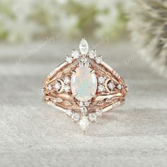 a white opal and diamond ring sitting on top of a table