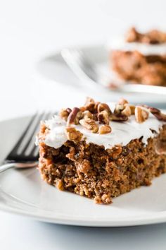 a piece of carrot cake on a white plate with a fork next to the slice