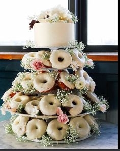 a three tiered wedding cake with donuts on the top and flowers on the bottom