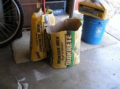 two bags of chips sitting on the sidewalk next to a bike and trash can in front of a building