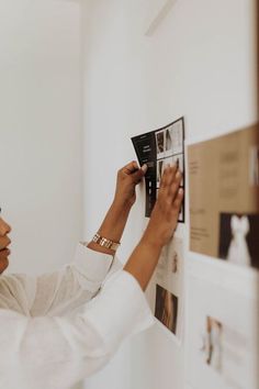 a woman placing pictures on the wall with her hands and looking at them as if she's doing something